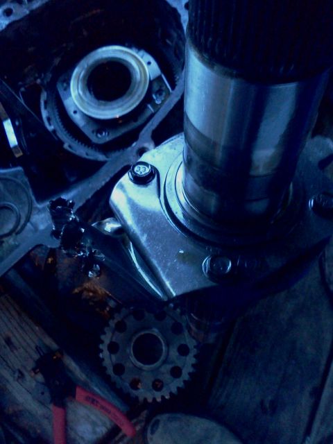 1989 Ford Bronco - Detail of a damaged automotive transmission part, with visible gears and a metal shaft.