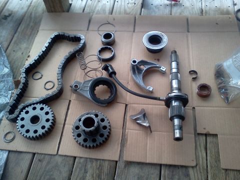 1989 Ford Bronco - Various transmission components are spread out on a wooden surface, suggesting a repair or rebuild process.