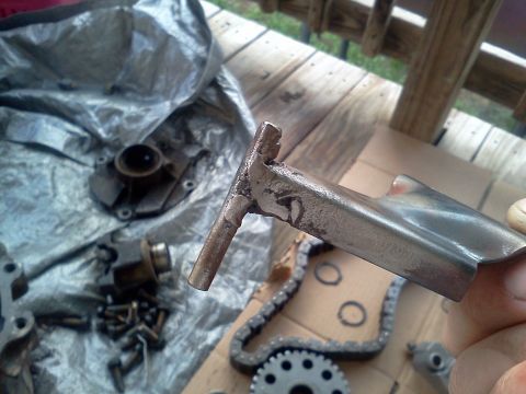1989 Ford Bronco - A disassembled engine part, likely from a timing system, is held in hand with other components and a chain visible.