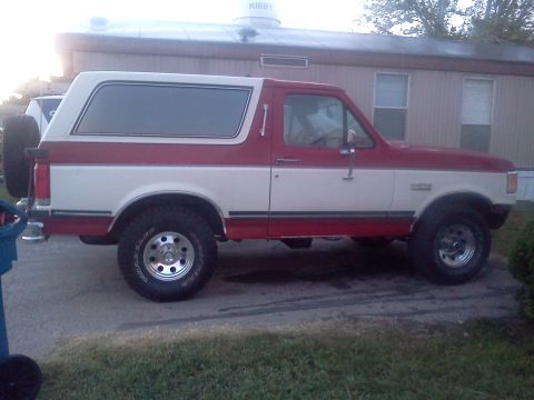 1989 Ford Bronco - This two-tone Ford Bronco is parked in front of a building with a water tower on the roof.