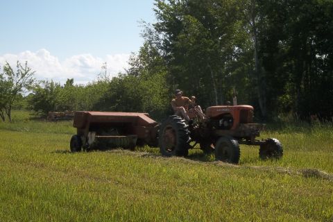 1987 Ford F-250 - A tractor is shown in a field, pulling a baler and harvesting hay.