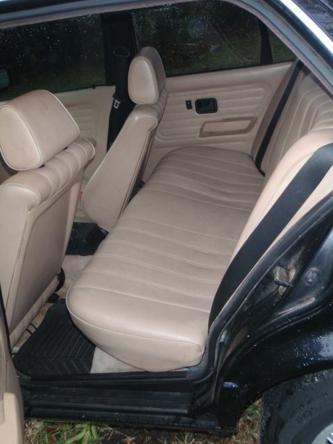 1991 BMW 3 Series - The interior of a car shows tan seats and door panels, with a black seatbelt visible.