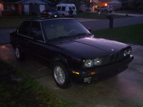 1991 BMW 3 Series - Black 1991 BMW 3 Series sedan seen from a 3/4 front angle in a residential driveway.