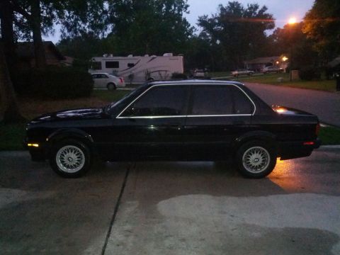 1991 BMW 3 Series - A black sedan is parked on a driveway at dusk, with a street and houses in the background.