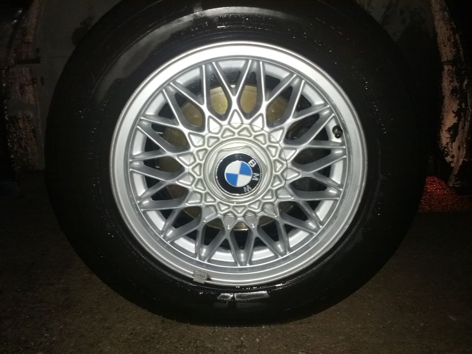 Close-up of a BMW alloy wheel with a tire. The BMW logo is visible on the center cap