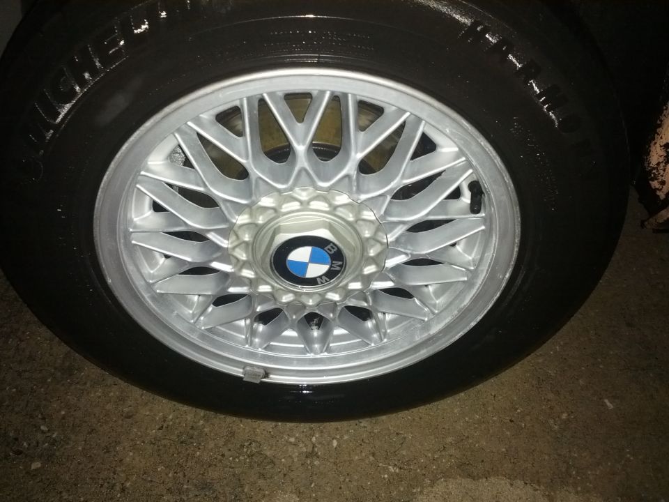 Close-up of a BMW wheel with a Michelin tire. The wheel has a silver mesh design and a BMW logo in the center