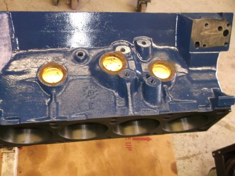 1967 Ford Mustang - A blue engine block is shown, with cylinders and oil passages clearly visible. Some text is present on the surface.