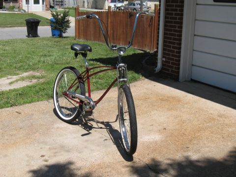1994 Ford Bronco - A red cruiser bicycle with tall chrome handlebars and white-wall tires sits on a concrete driveway.