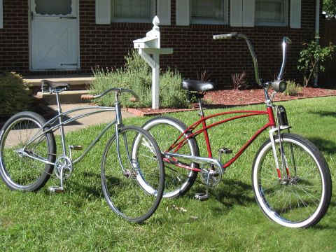 1994 Ford Bronco - A pair of classic cruiser bicycles, one in red and the other in silver, are parked on a grassy lawn in front of a brick house.