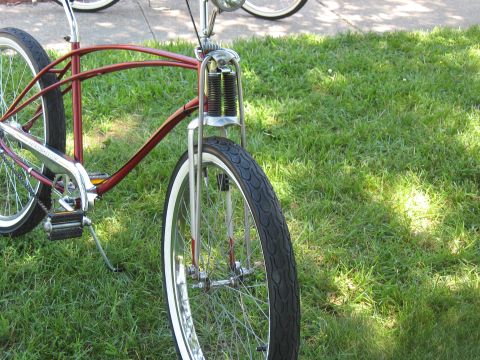 1994 Ford Bronco - A red cruiser bicycle with whitewall tires and chrome accents is parked on a grassy lawn.
