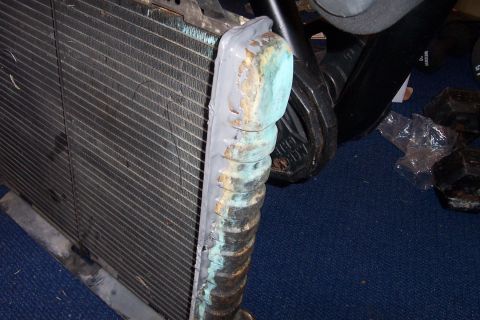 1980 Ford Bronco - A radiator part shows signs of repair with JB weld on its tanks and bent fins.