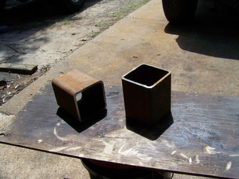 1985 Ford Bronco - Two steel tubes, one lying down and one standing upright, are on a weathered wooden surface.
