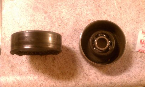 1995 Ford Bronco - A worn pulley and a pulley housing with a bearing are shown on a countertop.