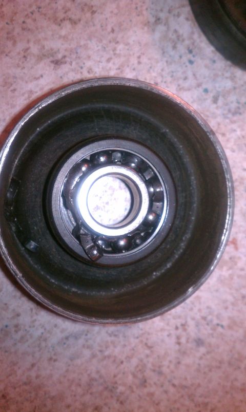 1995 Ford Bronco - Close-up view of a damaged wheel bearing assembly, with visible ball bearings and a bent retainer clip.