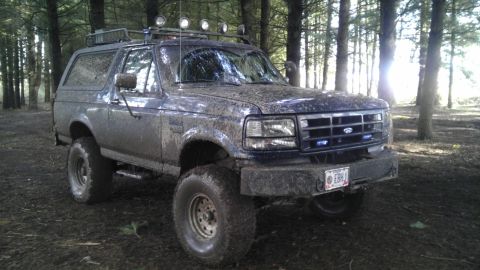 1995 Ford Bronco - This heavily muddied Ford Bronco is equipped for off-road adventures in a wooded area.