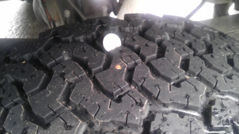 1995 Ford Bronco - Tire tread detail with a coin for scale.
