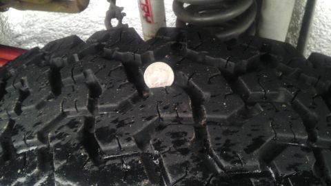 1995 Ford Bronco - A quarter is placed on the tread of a tire, showing the depth of the grooves.