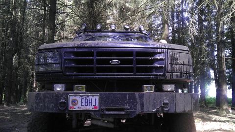 1995 Ford Bronco - This Ford F-Series truck, likely from the early to mid-1990s, is covered in mud and parked amongst trees.