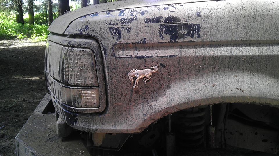Mud-covered 1995 Ford Bronco front fender with running horse emblem