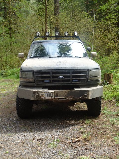1995 Ford Bronco - Front view of a 1995 Ford Bronco parked on a dirt road in a wooded area.