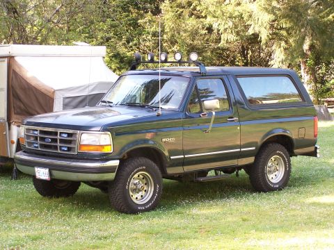 1995 Ford Bronco - This 1995 Ford Bronco is parked on a grassy area with trees in the background.