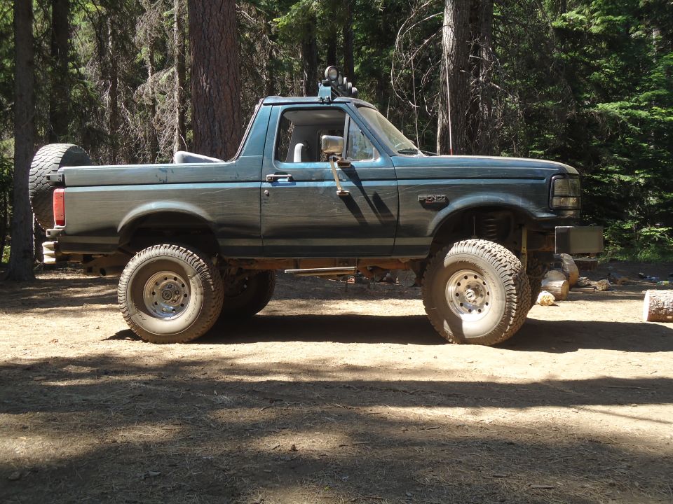 Teal lifted 1995 Ford Bronco side view with spare tire on back