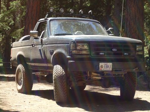 1995 Ford Bronco - This Ford Bronco is parked in a wooded area, showing its front end and lifted suspension.