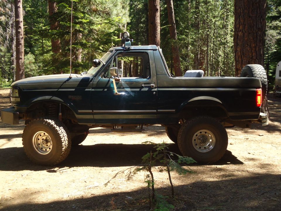 Dark green and gray 1995 Ford Bronco with off-road tires, lifted suspension, and spare tire mounted on the rear