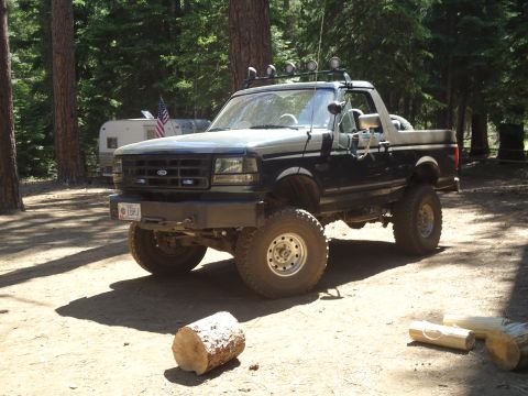1995 Ford Bronco - This lifted 1995 Ford Bronco, seen in a wooded area, features off-road lights and a two-tone paint scheme.