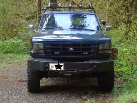 1995 Ford Bronco - Front view of a dark green 1995 Ford Bronco, modified with an aftermarket bumper and roof-mounted lights.