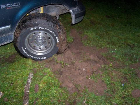1995 Ford Bronco - A 1995 Ford Bronco XLT is stuck in the mud, with its front tire partially submerged in dirt.