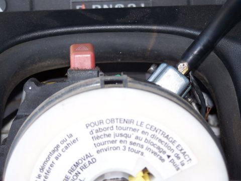 1995 Ford Bronco - Close-up of steering column components, including a red hazard light button and warning labels in French and English.
