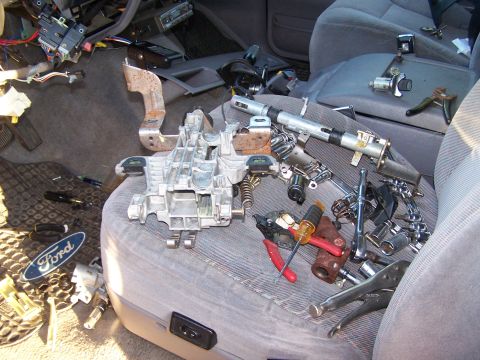1995 Ford Bronco - The interior of a vehicle is shown with the steering column disassembled and tools scattered around.