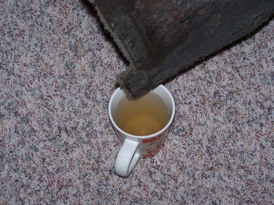 Bed liner edge dripping into a mug of liquid on carpet
