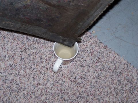 1995 Ford Bronco - A bed liner is shown with a mug of liquid placed beneath its edge on a carpeted surface.