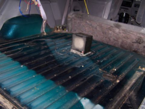 1995 Ford Bronco - The cargo area of a vehicle shows a ribbed floor with some dirt and a small speaker box.