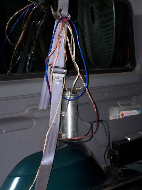 1995 Ford Bronco - Wires are bundled and hang from a seatbelt anchor inside a vehicle, near a first aid kit.