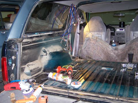 1995 Ford Bronco - Tools and wiring are visible inside the rear of a teal SUV, suggesting ongoing work.