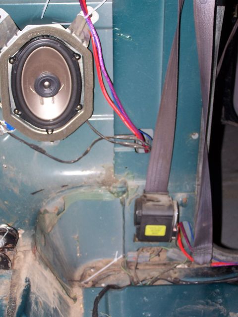 1995 Ford Bronco - Close-up of a car's interior showing a speaker and seatbelt mechanism with wiring.