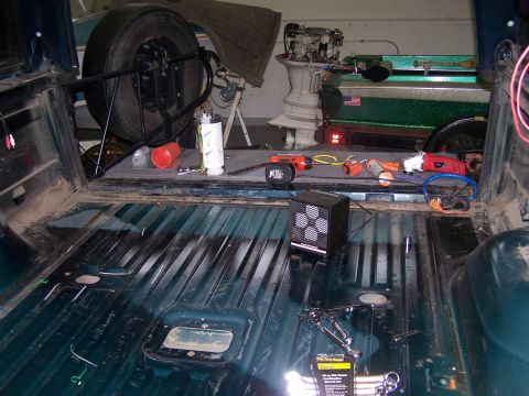 1995 Ford Bronco - The interior of a 1995 Ford Bronco shows a spare tire, various tools, and a boat motor in the background.