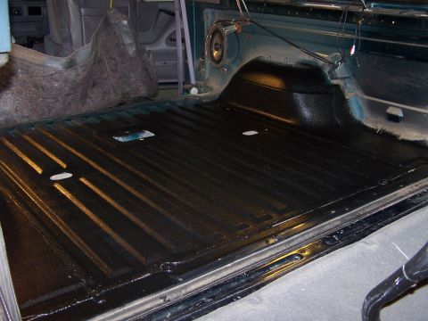 1995 Ford Bronco - Vehicle bed liner with black coating and ribbed texture.
