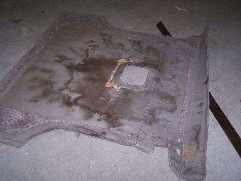 1995 Ford Bronco - A worn car floor mat with visible water stains and a central square cutout is shown.
