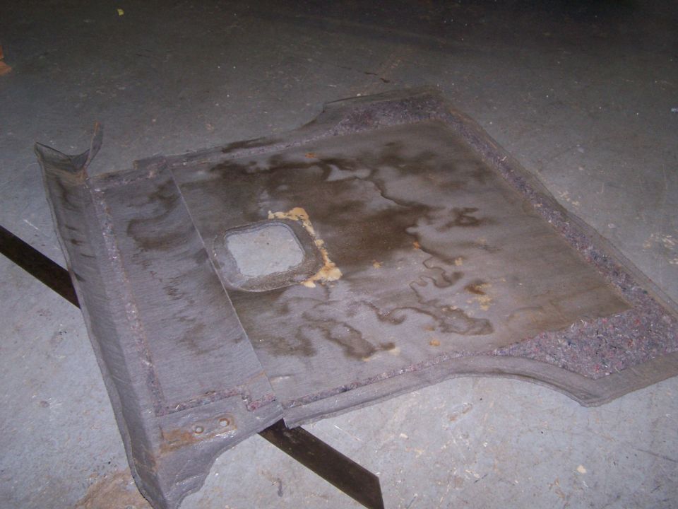 Worn carpeted cargo area liner with stains and a square cutout