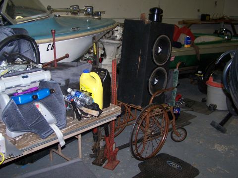1995 Ford Bronco - A cluttered garage contains a boat, car seat, large speaker system, and fluids.