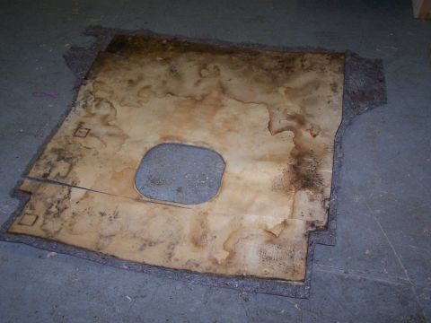 1995 Ford Bronco - This is a worn carpet liner with a cutout and visible stains, likely from a vehicle's interior.