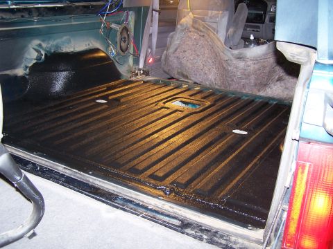 1995 Ford Bronco - The interior of a vehicle's cargo area has been coated with a black, textured bed liner.