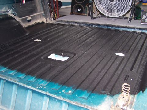 1995 Ford Bronco - The ribbed bed liner of a teal vehicle is visible, with some blue paint showing along the edges.