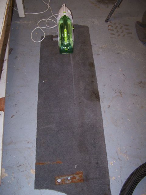 1995 Ford Bronco - A carpet cleaner sits on a carpeted area on a concrete floor, with a vacuum hose visible.