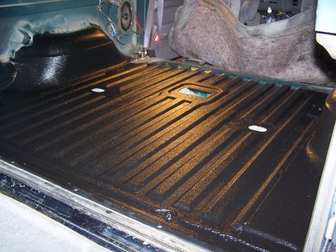 1995 Ford Bronco - The interior of a truck bed shows a freshly applied black liner with a ribbed pattern.