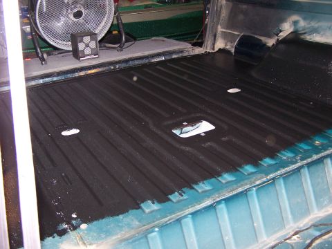 1995 Ford Bronco - The bed of a truck is being lined with a black protective coating.